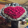 Heart-shaped bouquet of red roses edged with baby's breath in black wrap