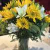Yellow sunflowers and white lilies in a glass vase
