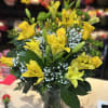 Yellow lilies and roses in a clear glass vase