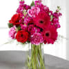 Bouquet of red roses and pink flowers in a clear glass vase
