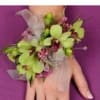 Green orchid wrist corsage with pink accents on a hand