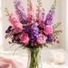 Pink and purple flowers arranged in a clear glass vase