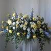 Large floral spray with yellow roses, white blooms, and blue flowers