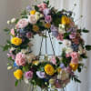Large floral wreath on a black stand with pastel roses and mixed blooms