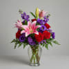 Pink lilies and red roses arranged in a clear glass vase