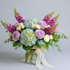 Bouquet of lavender roses, blue hydrangeas, and purple snapdragons in a glass vase
