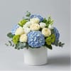 Blue hydrangeas and white roses arranged in a white vase
