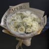 Bouquet of white roses wrapped in cream paper with a ribbon