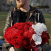 Large red floral arrangement in a black hatbox with white orchids and pearl strands