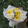 Bouquet of yellow gerbera daisies and white roses wrapped in white paper