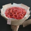 Bouquet of coral-pink roses wrapped in pale paper