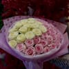 Bouquet of pink and cream roses wrapped in heart-patterned paper