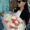 Woman holding a bouquet of pink and white flowers wrapped in translucent paper