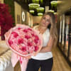 Woman holding a large bouquet of pink roses wrapped in pale pink paper