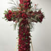 Cross-shaped arrangement of red roses with wispy greenery on a stand