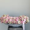 Low arrangement of pink and cream roses in a gray container