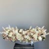 Low arrangement of cream and blush roses in a gray container