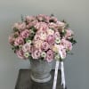 Pink rose bouquet in a gray urn vase with ribbon tails