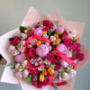 Large bouquet of pink roses, peonies, and tulips wrapped in pale pink paper