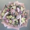 Bouquet of pale pink and cream roses with lavender blooms wrapped in pink paper
