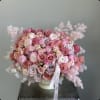 Pink and blush rose bouquet in a white vase with feathery accents