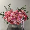Large pink rose arrangement in a gray vase with ribbon tails