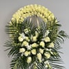 White rose funeral wreath with palm fronds and white orchids