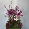 Pink and white orchid arrangement in a white bowl vase