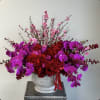 Red roses and purple orchids in a white vase with pink blossoms