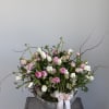 Pink and white floral arrangement in a stone bowl with ribbon