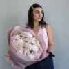 Woman holding a large bouquet of pale pink and white flowers wrapped in pink paper