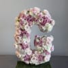 Large floral letter C made of pink and white roses on a moss base