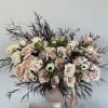 Lush arrangement of soft blush roses and delicate anemones, accented with airy