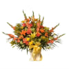 Orange and yellow mixed flower arrangement in a vase with a gold ribbon