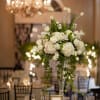 Tall white floral centerpiece in a clear vase on a banquet table