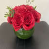 Red roses arranged in a green glass vase