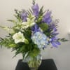 White lilies and blue-purple flowers in a glass vase