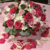 Pink and white rose arrangement in a white vase on a pink table