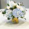 Blue and white flower arrangement in a glass vase with lemons