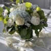 White and pale blue floral centerpiece in a glass vase