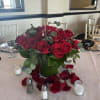 Red rose centerpiece in a glass vase with scattered petals