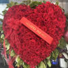 Heart-shaped bouquet of red roses with a ribbon and card