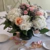 Pink and white floral centerpiece in a dark vase on a set table