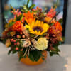 Autumn bouquet with sunflowers, orange roses, and a pumpkin vase