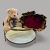 Red rose bouquet with a teddy bear and chocolate box on a glass table