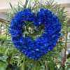 Heart-shaped wreath of vivid blue roses with palm fronds
