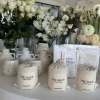 White floral arrangements with roses, ranunculus, and daisies in ceramic vases