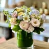 Pastel mixed flower arrangement in a green glass vase