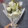 White roses and lilies in wrapped bouquet with gold ribbon