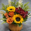 Orange roses and sunflowers in a pumpkin-shaped vase with red alstroemeria